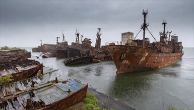 Rusty and abandoned shipwrecks in the water under dark clouds in a melancholic atmosphere, symbol