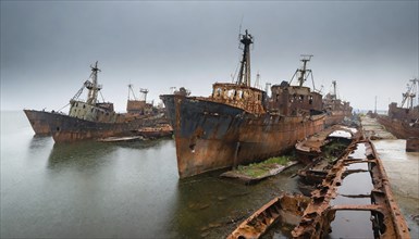 Dilapidated and rusty shipwrecks in an abandoned harbour under a grey, cloudy sky, symbol photo