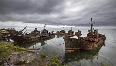 Dilapidated shipwrecks in the sea under a cloudy sky, gloomy and melancholic atmosphere, symbolic