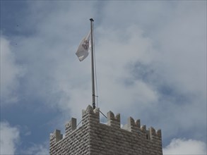 A medieval tower with a waving flag against a cloudy sky, monte carlo, monaco, france