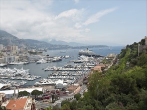 Panorama of the harbour with many yachts and boats, surrounded by a coastline and green hilly