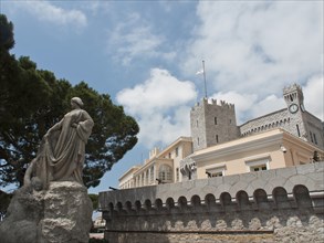 Statue with a castle in the background showing a clock tower and parts of the architecture, monte