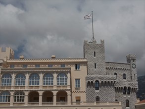 Historic castle with towers and waving flag in front of a cloudy sky, monte carlo, monaco, france