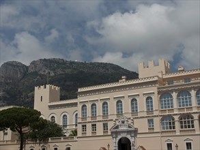 White fortress building with mountains in the background under a cloudy sky, monte carlo, monaco,