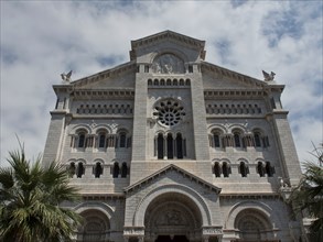 Impressive church façade with palm trees in the foreground and cloudy sky, monte carlo, monaco,