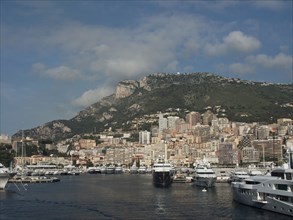 The harbour full of yachts surrounded by a city with a mountain landscape and cloudy sky in the