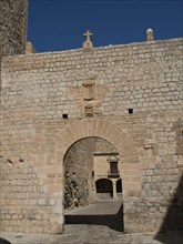 A sandstone arch in a medieval castle complex under a clear sky, ibiza, mediterranean sea, spain