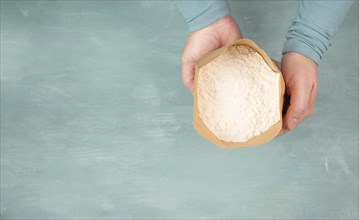 Baker holds paper bag with white wheat flour, baking ingredient for bread, pizza or pastry