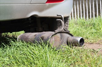 Broken exhaust and muffler of a car, rusted silencer fallen down on the road, breakdown of vehicle