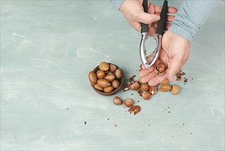 Crack nuts with a nutcracker, mix variety of almonds, hazelnuts and pecan nuts, healthy food and