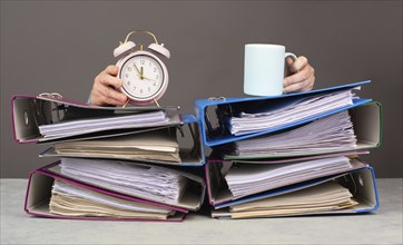 Exhausted tired woman with coffee and alarm clock, pile of file folders, burnout, stress and