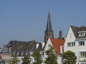 View of several houses with a church tower in the background, under a sunny sky, Maastricht,