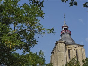 Church tower with red details, framed by green trees and blue sky, Maastricht, limburg, the