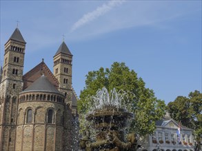 A fountain bubbles in front of a historic church building with two towers, Maastricht, limburg,