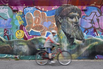 God of Greek mythology, Zeus, large graffiti on building fence, cyclist, harbour, Gothenburg,