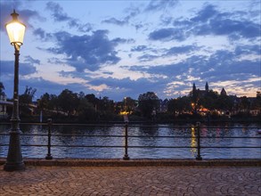 Quiet riverside scene at dusk with street lamp and clouds in the sky, Maastricht, limburg, the