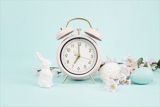 Cute easter bunny or rabbit with an alarm clock, eggs and cherry blossoms, spring holiday, greeting
