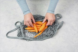 Unpack fresh carrots from a reusable grocery mesh bag, vegetables from the market, healthy food and