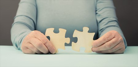 Holding two pieces of a puzzle in the hands, connecting together as a team, solving a problem,