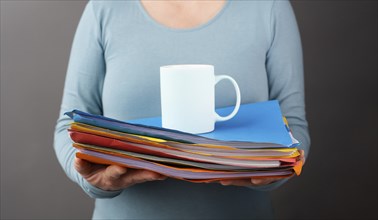 Woman with a pile of file folders and a cup of coffee, work at the office, stress and burn out,