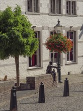 Historic town square with lantern, hanging basket, tree and a bronze sculpture, Maastricht,