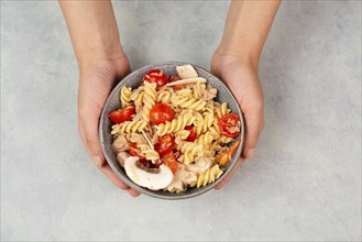 Pasta salad in a bowl, sliced mushroom, tomato, red pepper pieces and tuna, healthy food with