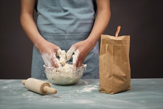 Baker kneading dough for artisan bread or pizza with his hands, prepare ingredients for food,