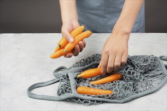 Unpack fresh carrots from a reusable grocery mesh bag, vegetables from the market, healthy food and