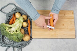 Peel carrot with scraper sharpener, prepare healthy food with vegetables, fresh organic nutrition,