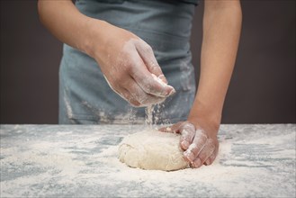 Baker kneading dough for pizza or artisan bread with his hands, prepare ingredients for food,