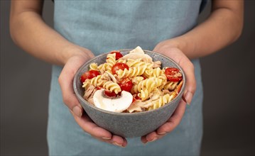 Pasta salad in a bowl, sliced mushroom, tomato, red pepper pieces and tuna, healthy food with
