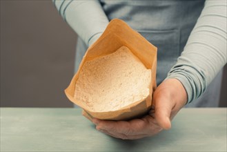 Baker holds paper bag with white wheat flour, baking ingredient for bread, pizza or pastry