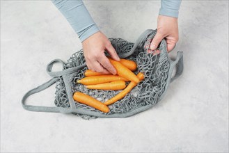 Unpack fresh carrots from a reusable grocery mesh bag, vegetables from the market, healthy food and