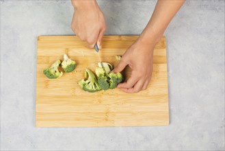 Cutting broccoli on a wooden board, prepare, healthy food with vegetables, fresh organic nutrition,