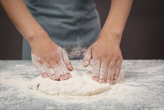 Baker kneading dough for pizza or artisan bread with his hands, prepare ingredients for food,