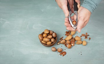 Crack nuts with a nutcracker, mix variety of almonds, hazelnuts and pecan nuts, healthy food and