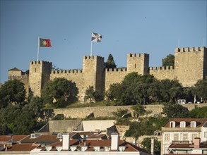 Stone castle with flags and trees under a blue sky, Lisbon, portugal