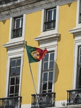 Yellow façade with windows, Portuguese flag waving in the wind, Lisbon, portugal