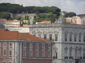Historic buildings with red roofs and green trees on a hilly landscape, Lisbon, portugal