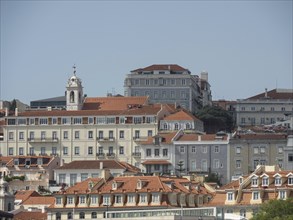 Urban scenery with historic houses and red tiled roofs under a clear sky, Lisbon, portugal
