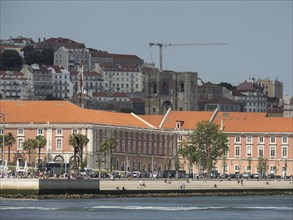 Historic buildings with red roofs and an old tower in a corresponding old town atmosphere, Lisbon,