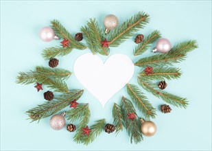 Christmas holiday background in heart shape, frame with fir branches, baubles and pine cones,