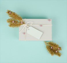 Gift box with a blank tag, golden colored fir branches and baubles, christmas holiday in winter