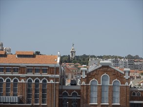View of a large brick building with towering windows and city in the background, Lisbon, portugal