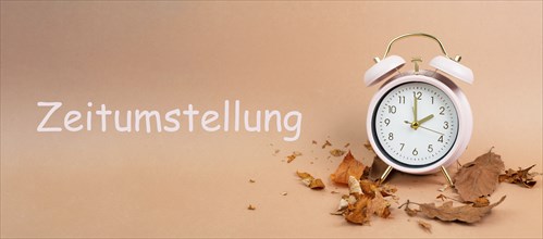 Alarm clock with autumn foliage, end of daylight saving time in fall, winter time changeover stands