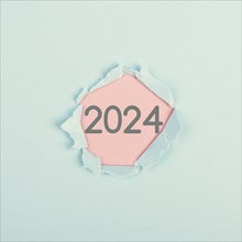 New year 2024 stands behind ripped paper, calendar date, end of the year, changing time, New Year's