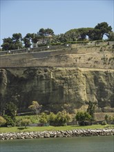 A steep cliff with trees and greenery on a sunny day, Lisbon, portugal