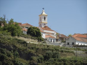 A church with a tower on a green hill under a clear sky, Lisbon, portugal