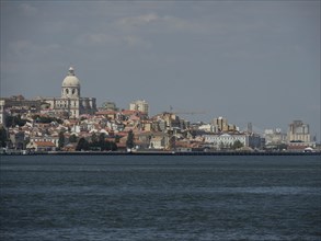 View of a city with many buildings and a large dome near a river, Lisbon, portugal