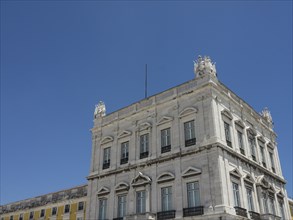 A classicist building with a white facade and several windows, under a clear blue sky, Lisbon,